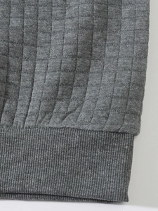 Detailed macro view of the vertical quilted texture and ribbed hem on a grey men hoodie