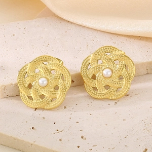 Détail de la boucle d'oreille fleur dorée avec texture tissée et une perle blanche centrale