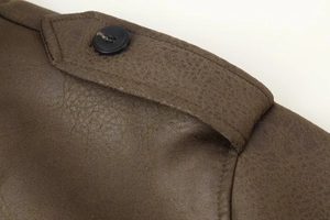 Detailed macro view of dark brown faux suede jacket shoulder with epaulet and black button