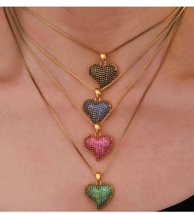 Close-up of four layered gold heart necklaces with black blue pink and green cubic zirconia