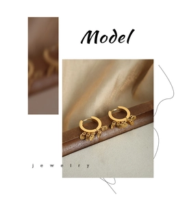 Détail de boucles d'oreilles dorées en U avec pendentifs éventails striés sur satin