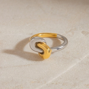 Detailed shot of two-tone knot ring in gold and silver finish on stone surface