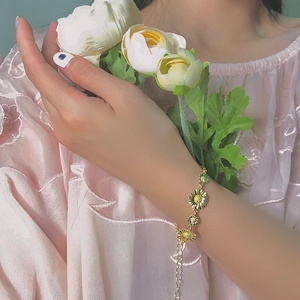 Detailed view of adjustable gold daisy bracelet with colorful enamel petals on model