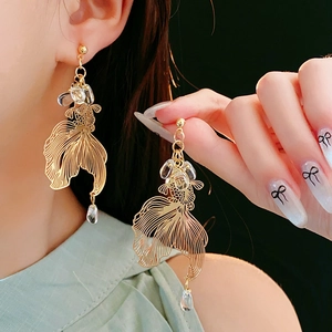 Detailed view of hollow gold koi fish earrings with elegant crystal water drop beads