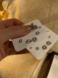 Close-up of a silver earring set with various sizes of round and square cubic zirconia stones