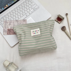Detailed view of striped fabric cosmetic bag with sozakka label among makeup accessories
