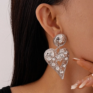 Close-up of a silver heart drop earring with crystal rhinestones on a female model