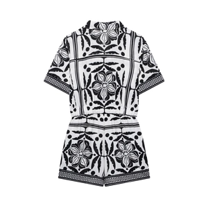 Back view of a black and white floral print romper with a Cuban collar and short sleeves