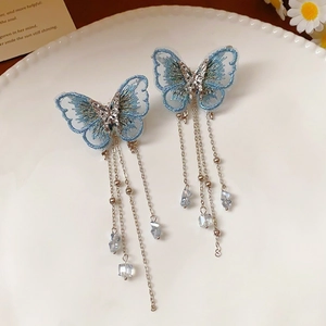 Vue détaillée des boucles d'oreilles papillon brodées bleues avec glands argentés