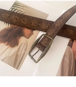 Detail of vintage embossed brown leather belt with ornate metal buckle on a magazine