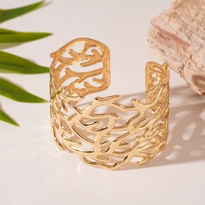 Detailed view of wide gold open bangle with intricate coral branch cutout texture
