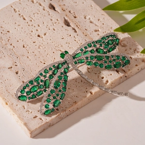 Detailed macro view of dragonfly brooch with green stones and sparkling zircon inlay