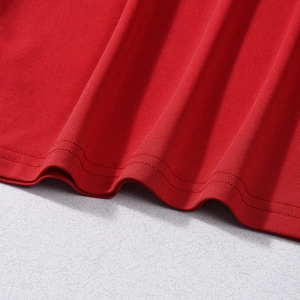 Close-up of red knitted top featuring professional double-stitch hem and fine fabric texture