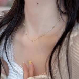 Detail of a minimalist gold S925 silver beaded choker necklace on a model