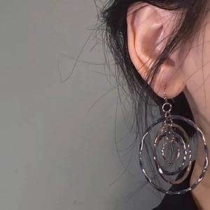Detail of silver layered ripple hoop earrings on model with multi-circle design