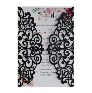 Detail of laser-cut black glitter wedding invitation cover with floral printed insert