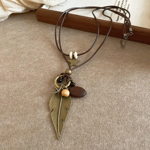Vintage ethnic style necklace with bronze leaf and star pendants on brown leather cord
