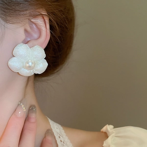 Close-up of white flower earrings with pearl accent worn by model for elegant style