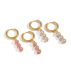Elegant gold earrings with white and pink zircon stones shown in professional still life view