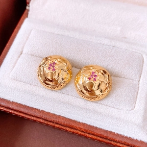 Detail of 18k gold plated vintage earrings with embossed texture and red stones