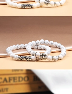 Macro detail of white marble beads and owl charm on a handmade beaded bracelet