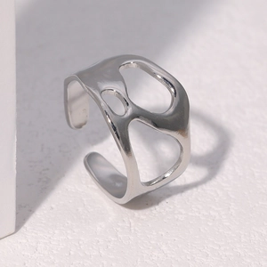 Macro d'une bague argentée ajourée irrégulière avec un éclat métallique poli