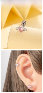 Macro detail and ear display of a heart-shaped angel wing earring with pink zircon