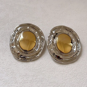Detail of twisted circular earrings featuring silver lava texture and gold metal center