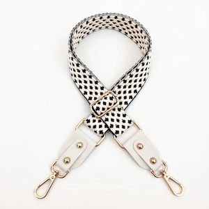 Macro detail of black and white jacquard strap with white leather and gold buckles