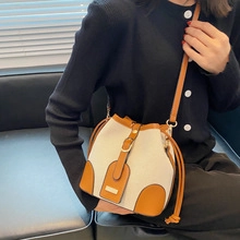 Detail of canvas bucket bag featuring contrast leather trim and drawstring closure