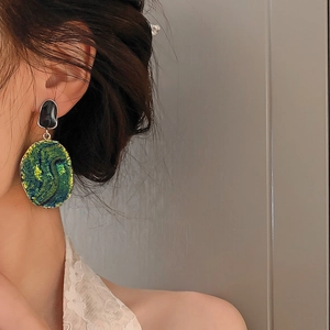 Vintage oval earrings in dark green oil painting style worn by a female model