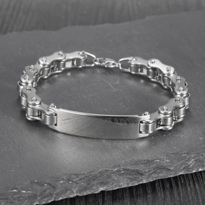 Polished stainless steel bicycle chain bracelet with metal plate on dark rock surface