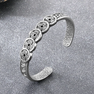 Macro detail of vintage silver steel cuff featuring Five Emperor coins and textured inner band