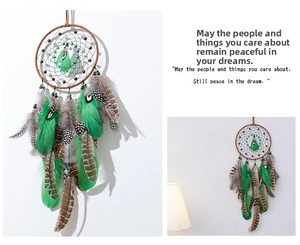 Detailed view of green and brown feathers on a handcrafted dream catcher wall hanging