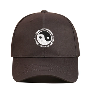 Close-up of white Tai Chi Yin Yang embroidery and Swimming text on brown baseball cap