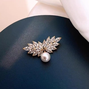 Macro detail of leaf-shaped brooch with marquise crystals and white pearl drop charm