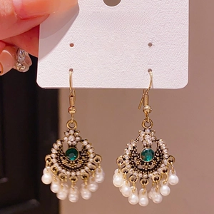 Detailed close-up of emerald floral earrings with pearls and golden vintage metal