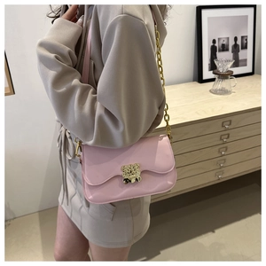 Détail latéral du sac à bandoulière rose avec chaîne dorée et fermoir ours en métal