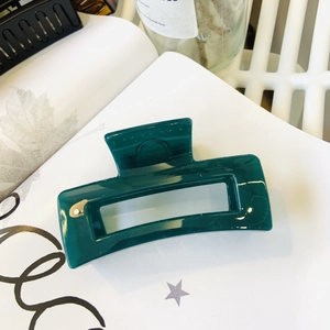 Detail of dark emerald green rectangular hair claw clip on lifestyle background