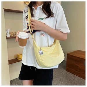 Close-up of bright yellow canvas crossbody bag with cute white poodle plush keychain