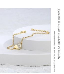 Detail of gold plated heart bracelet featuring zircon pavé and polished metal surfaces