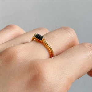 Detail of a gold rope-textured ring featuring a rectangular black zircon on a finger