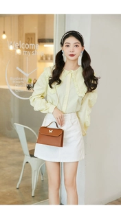 Close-up of stylish brown leather crossbody bag with butterfly decor on a model