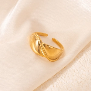 Détail d'une bague dorée mate torsadée géométrique sur de la soie blanche et tissu texturé