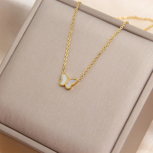 Elegant gold butterfly shell pendant necklace displayed on a textured jewelry box