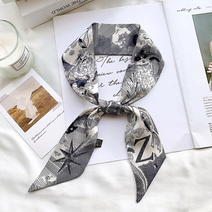 Detail of a black and white silk twilly scarf with lion and Z pattern on a magazine