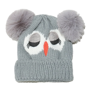 Detail of owl face embroidery and grey faux fur pom-poms on children's knitted hat