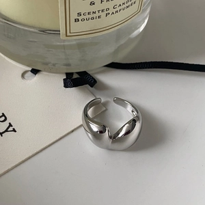 Macro detail of polished liquid metal heart ring styled with candles and ribbons