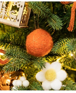 Close-up of plush orange felt ball ornament with gold thread on a Christmas tree