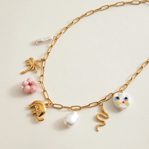 Detail of gold chunky chain necklace with pearl, palm tree, snake and elephant charms